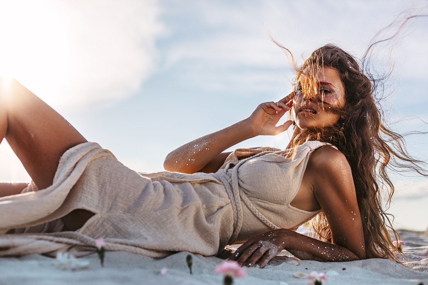 Woman resting on a sunlit beach in relaxed cream linen