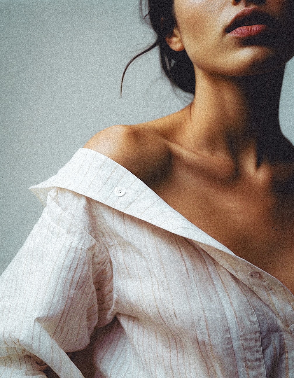 Neck and collarbones above an open white shirt in soft natural light