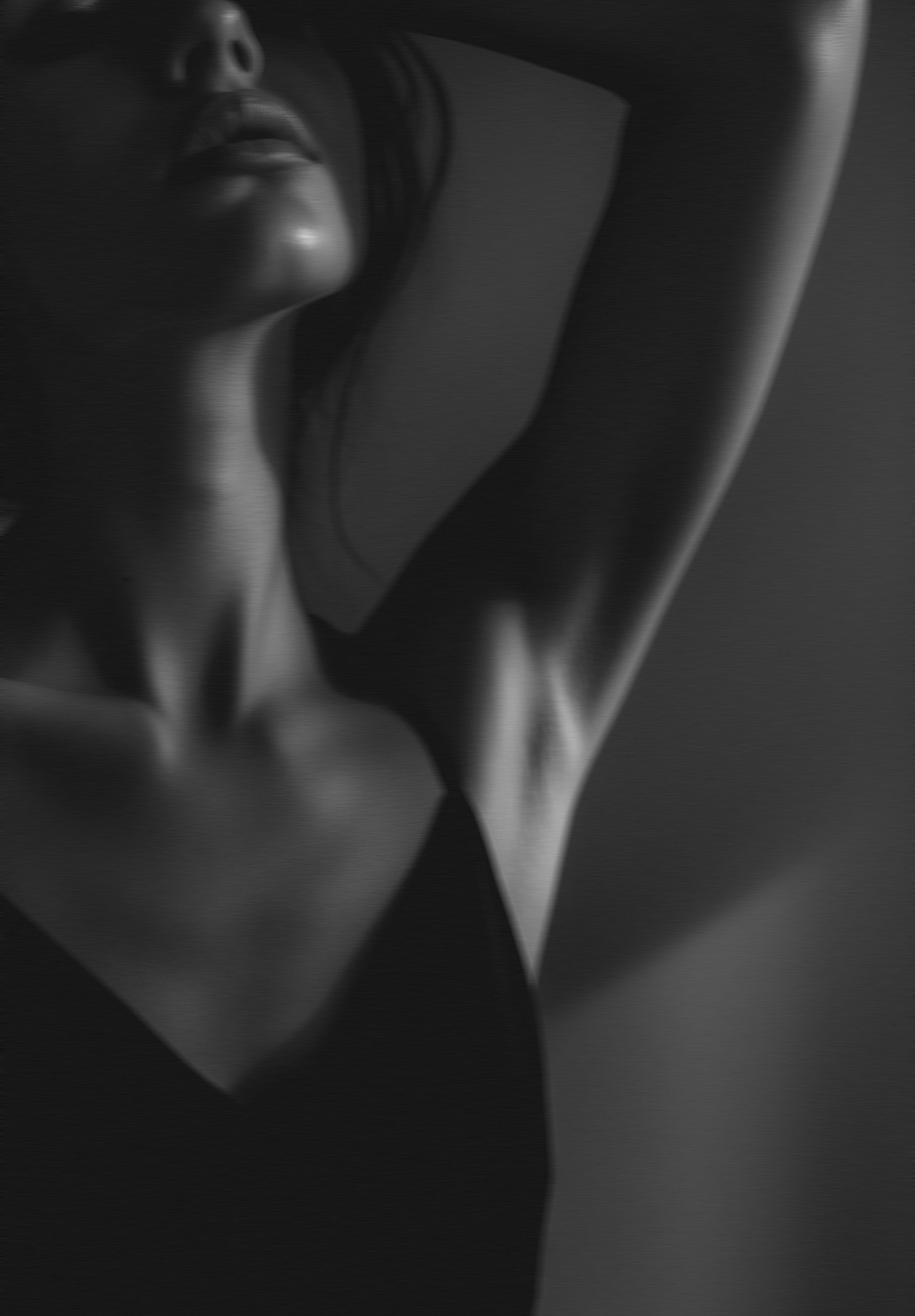 Black-and-white composition highlighting a neck, collarbones and a raised shoulder