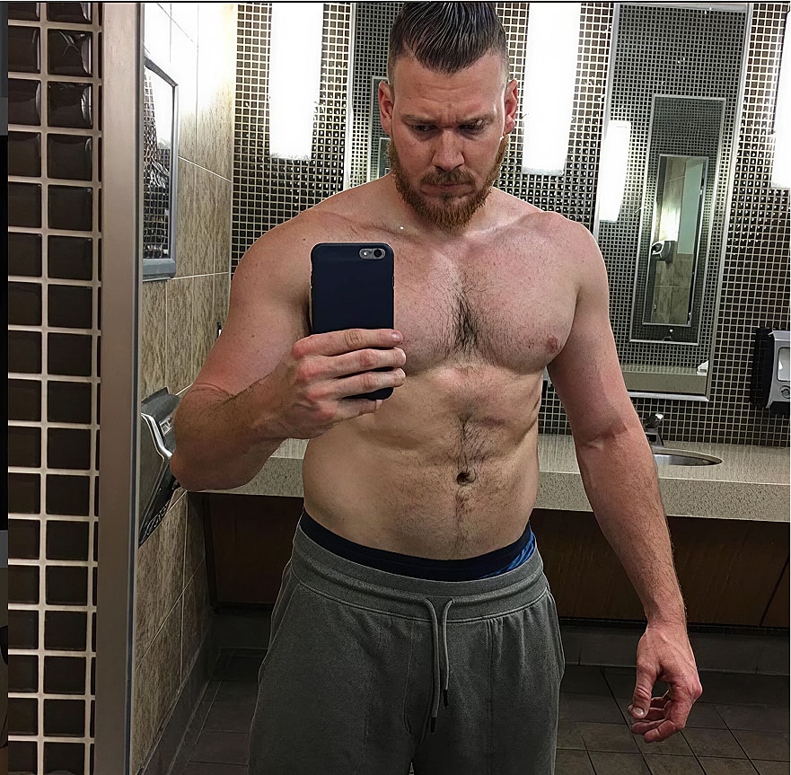 Man taking mirror selfie in fitness center.