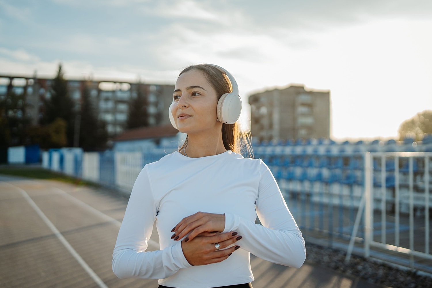 Woman in workout clothes wearing headphones outdoors, illustrating exercise after breast reduction recovery.