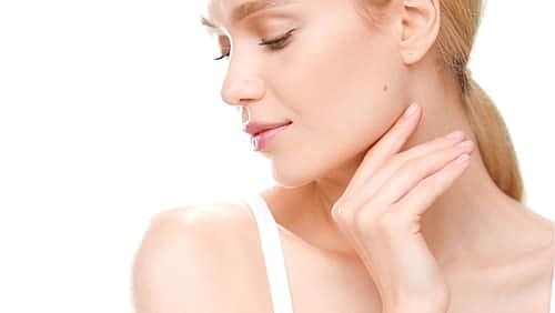 Caucasian woman with golden hair in white crop top touches her jaw line turning her head aside