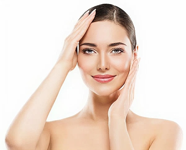 A woman framing her face with her hands and showing the results of cheek filler.