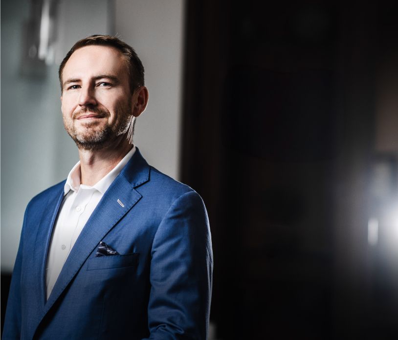 Man in a blue suit smiling confidently.