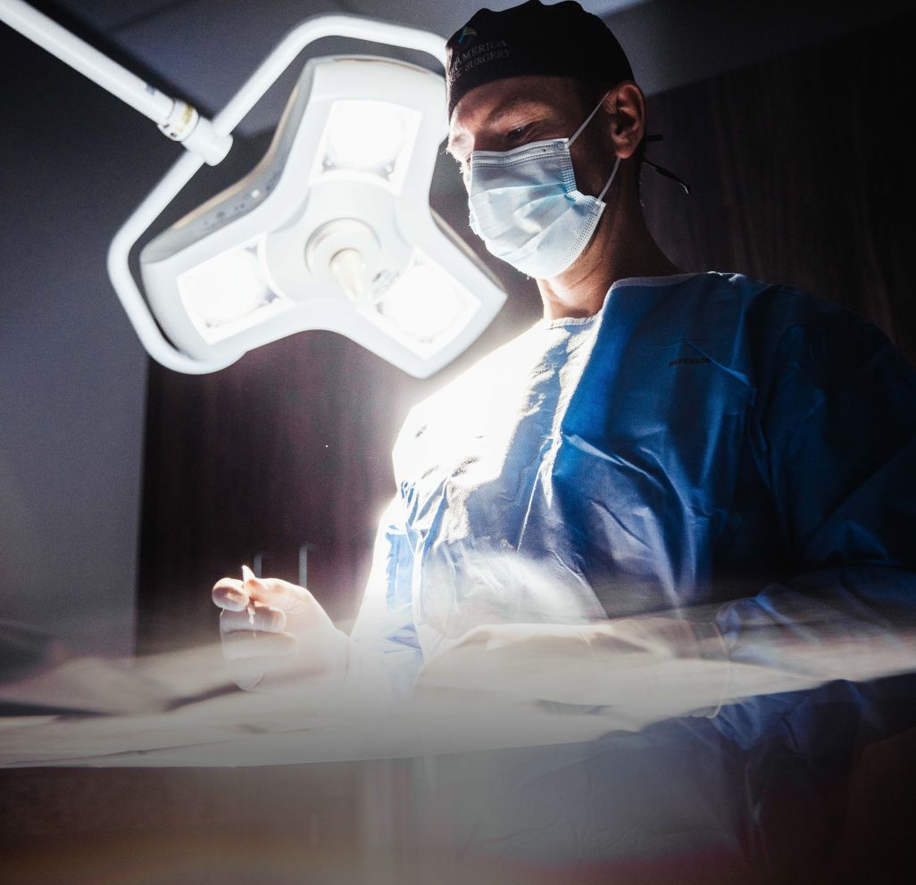 Surgeon performing procedure under bright surgical lights.