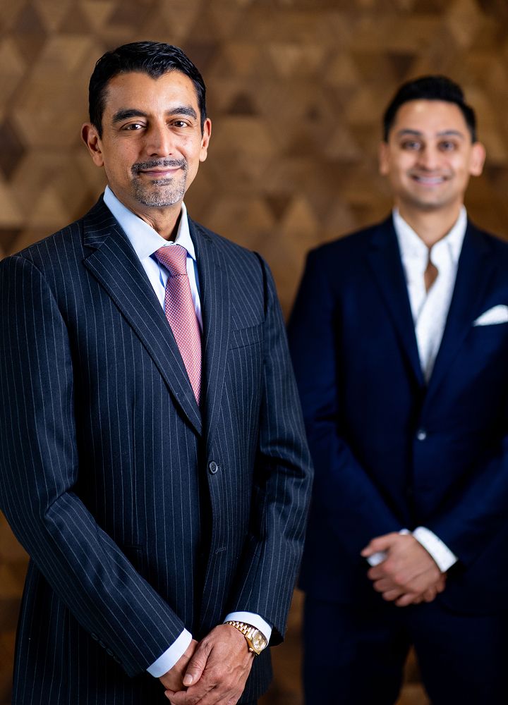 Two men in formal business attire, smiling confidently.