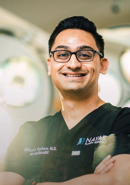 Smiling doctor in scrubs with confident demeanor.