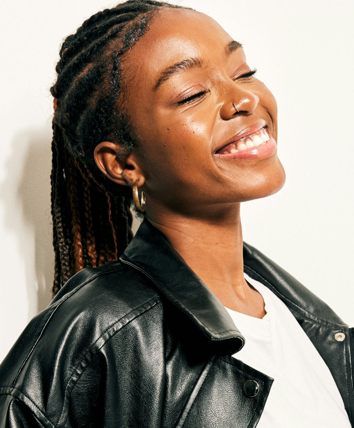 Woman smiling with braided hair in leather jacket.