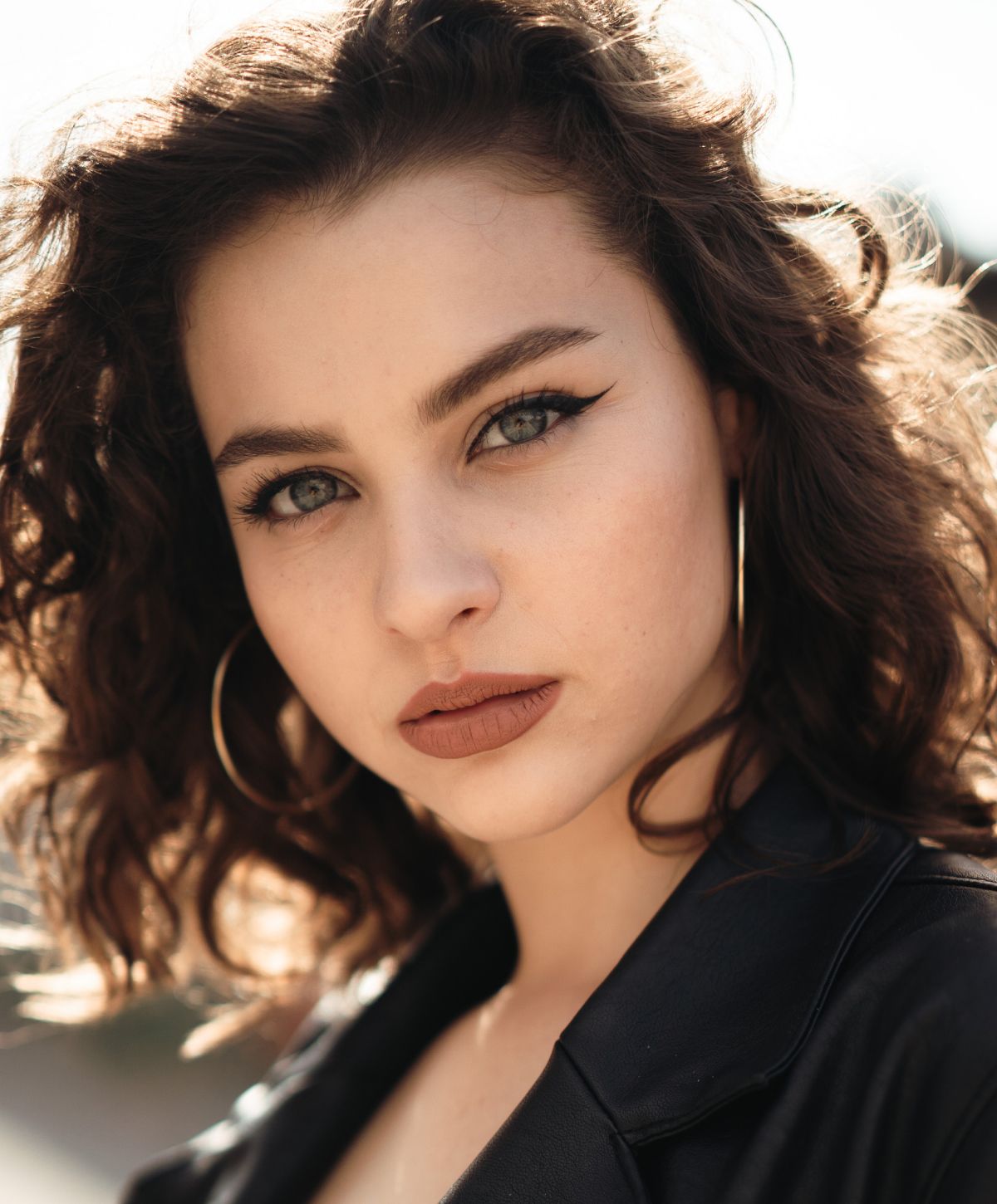 Young woman with curly hair and hoop earrings.