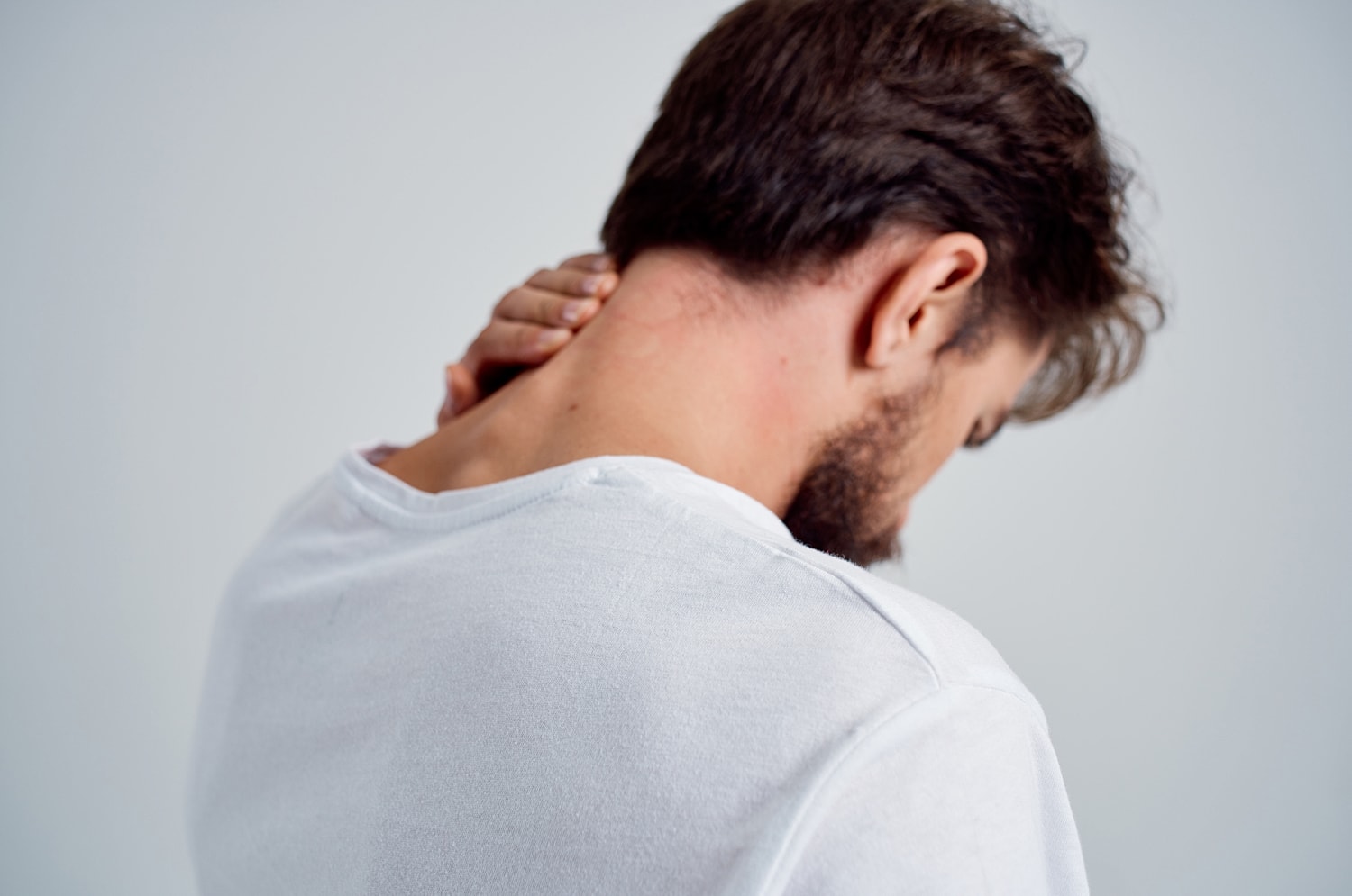 Man rubbing his neck in discomfort.