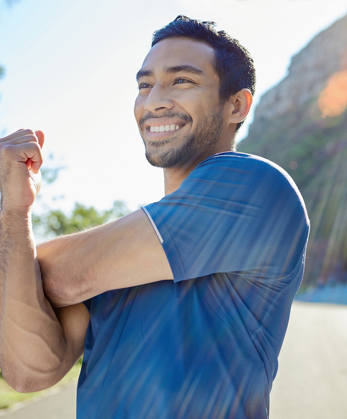 Smiling herniated disc treatment patient model stretching outdoors in athletic wear.