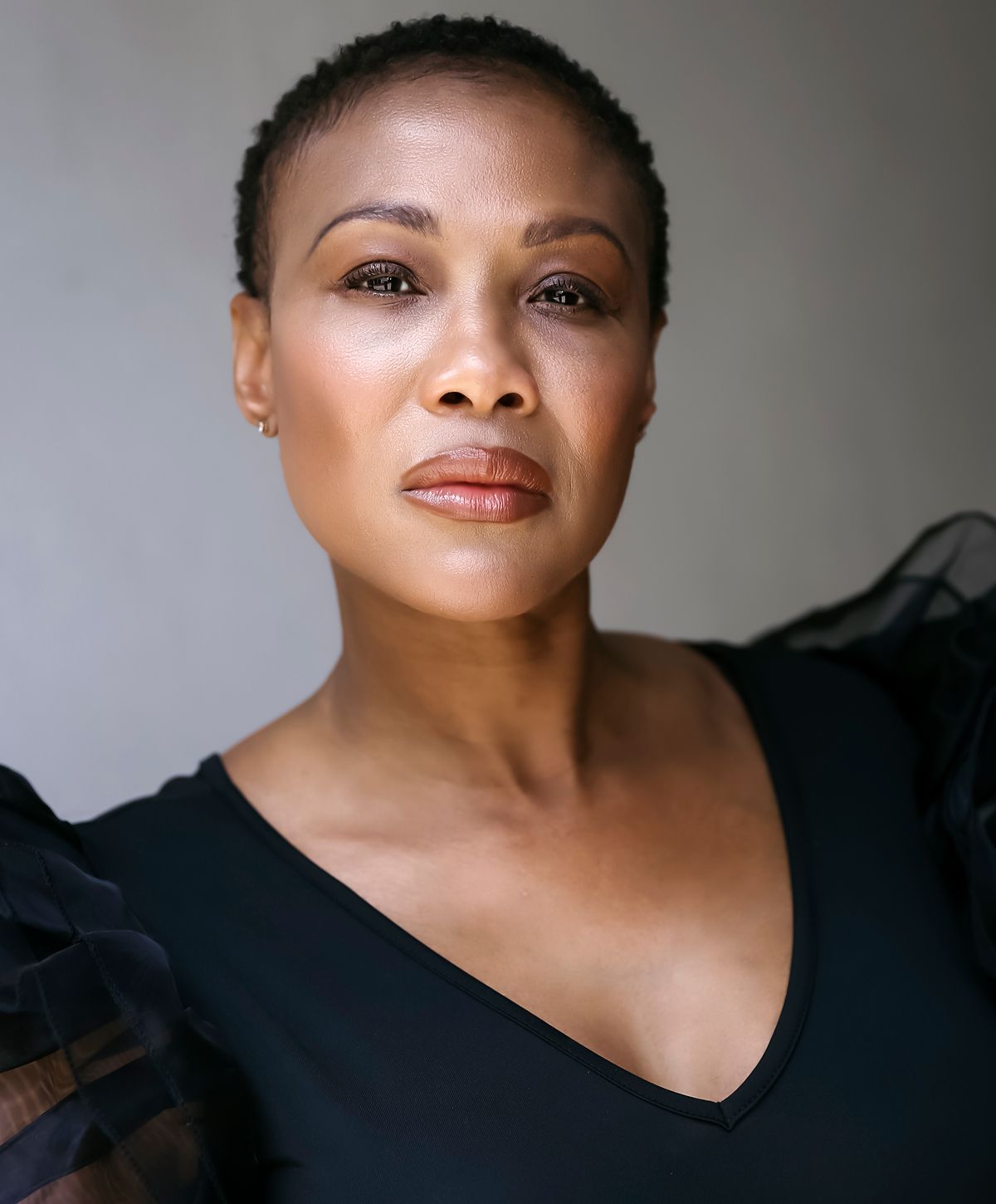 Woman posing with arm raised, natural lighting.