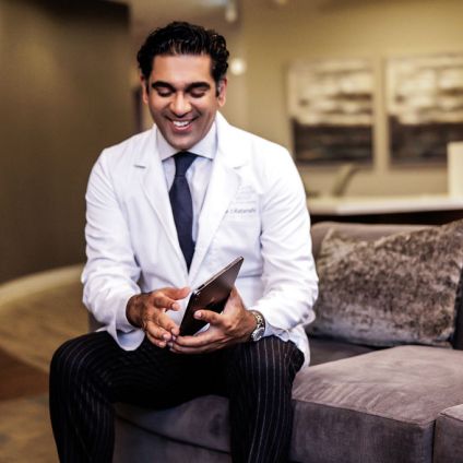 dr ratanshi smiling and using an ipad