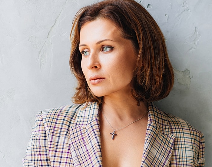 Woman in a plaid blazer with contemplative expression.