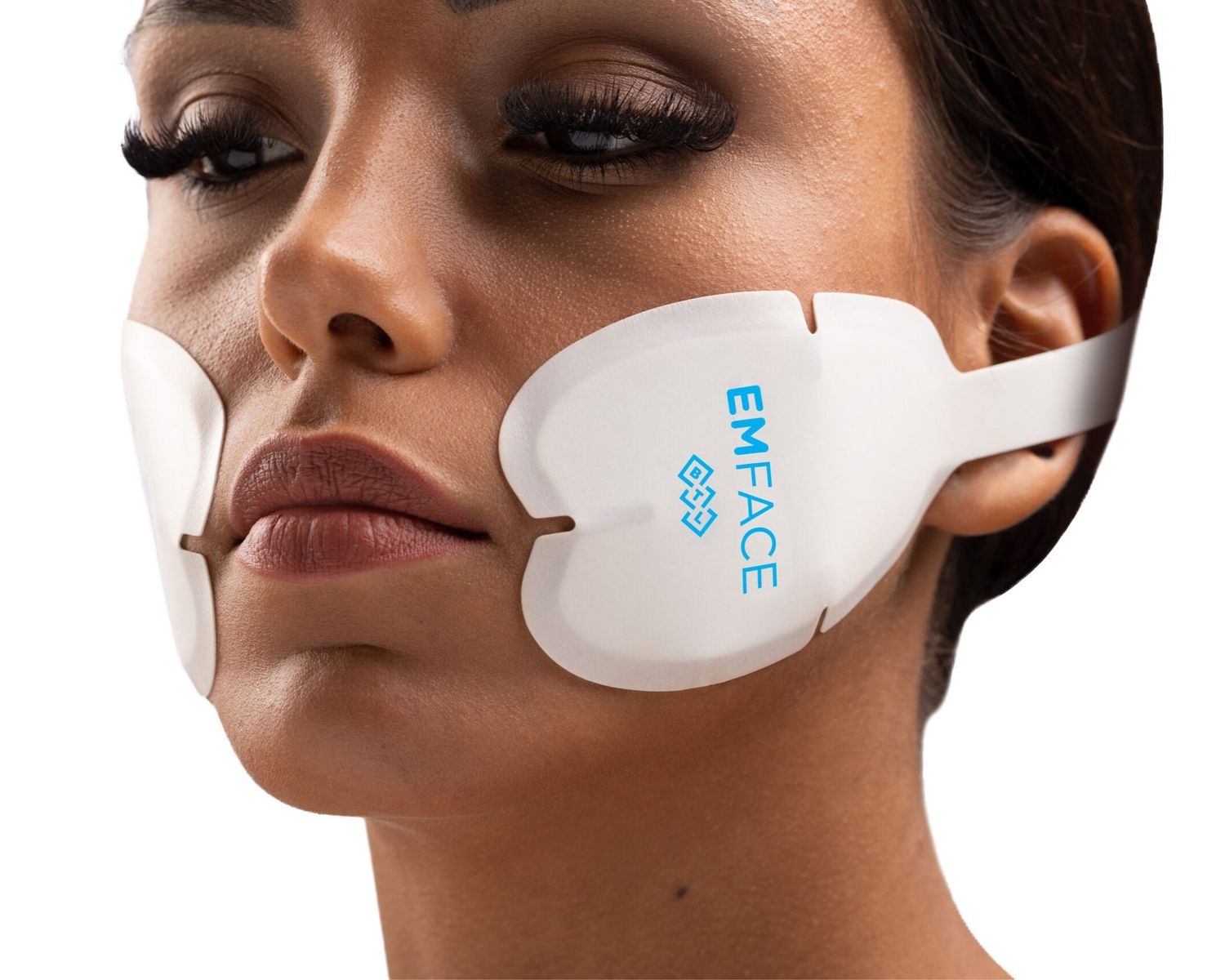 Woman using EMFACE facial treatment device.