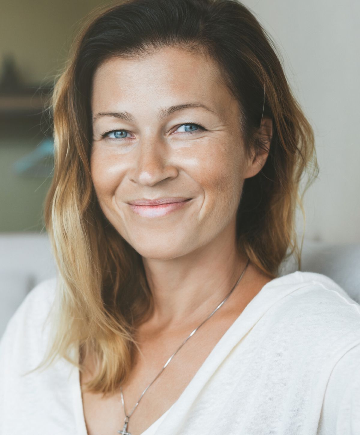 Smiling woman with long hair and necklace.
