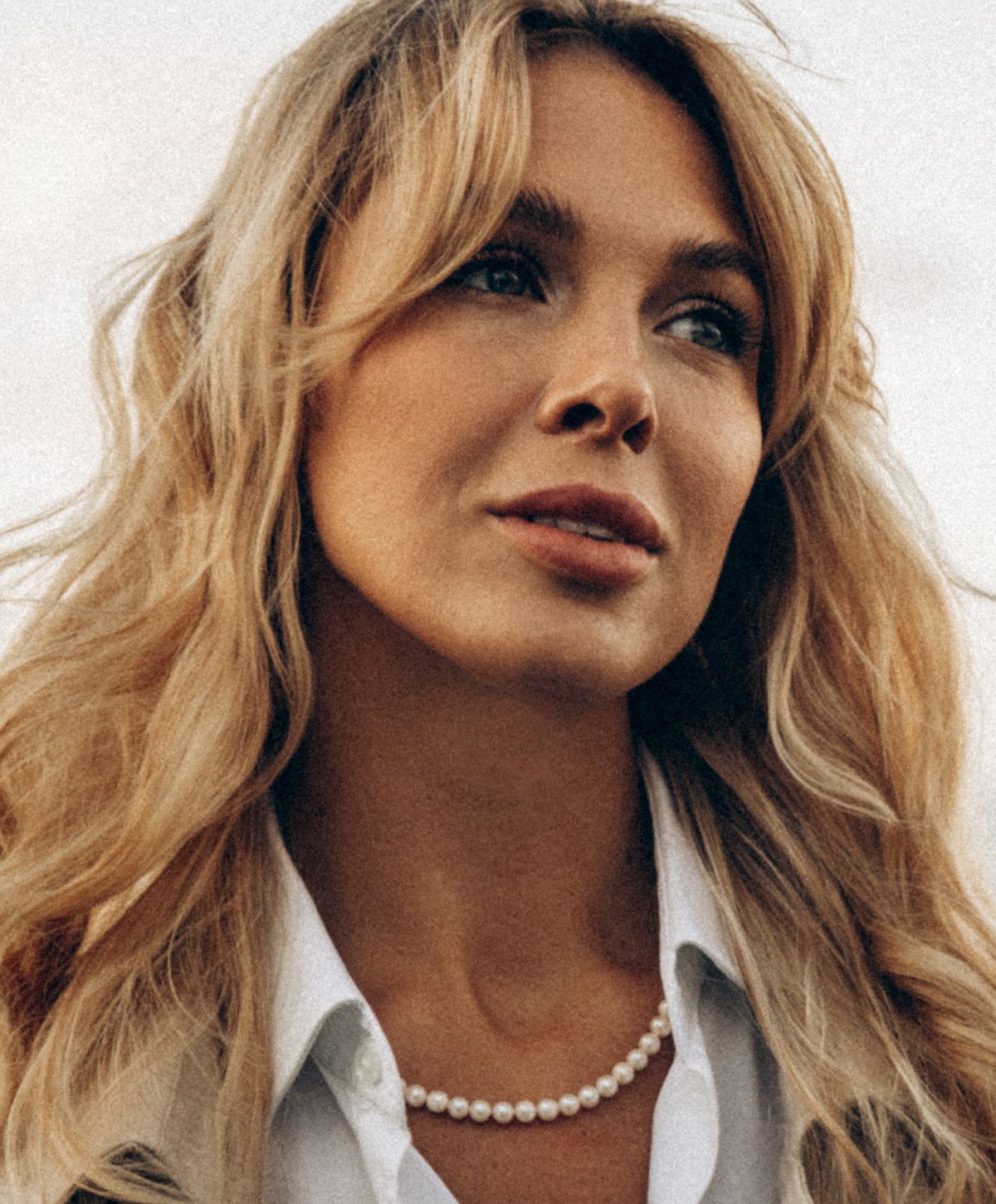 Woman with blonde hair and pearl necklace.
