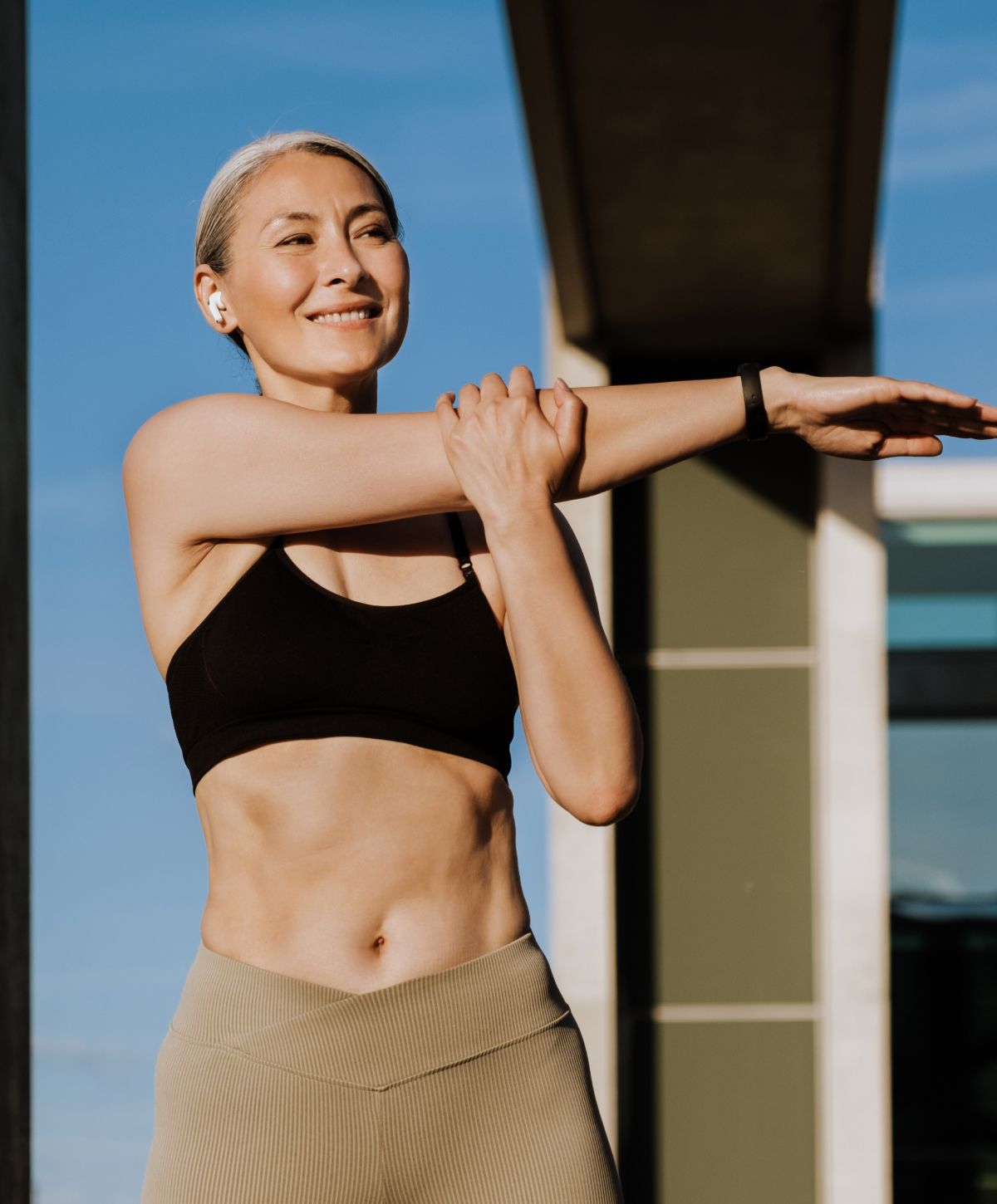 Woman stretching outdoors in athletic wear.