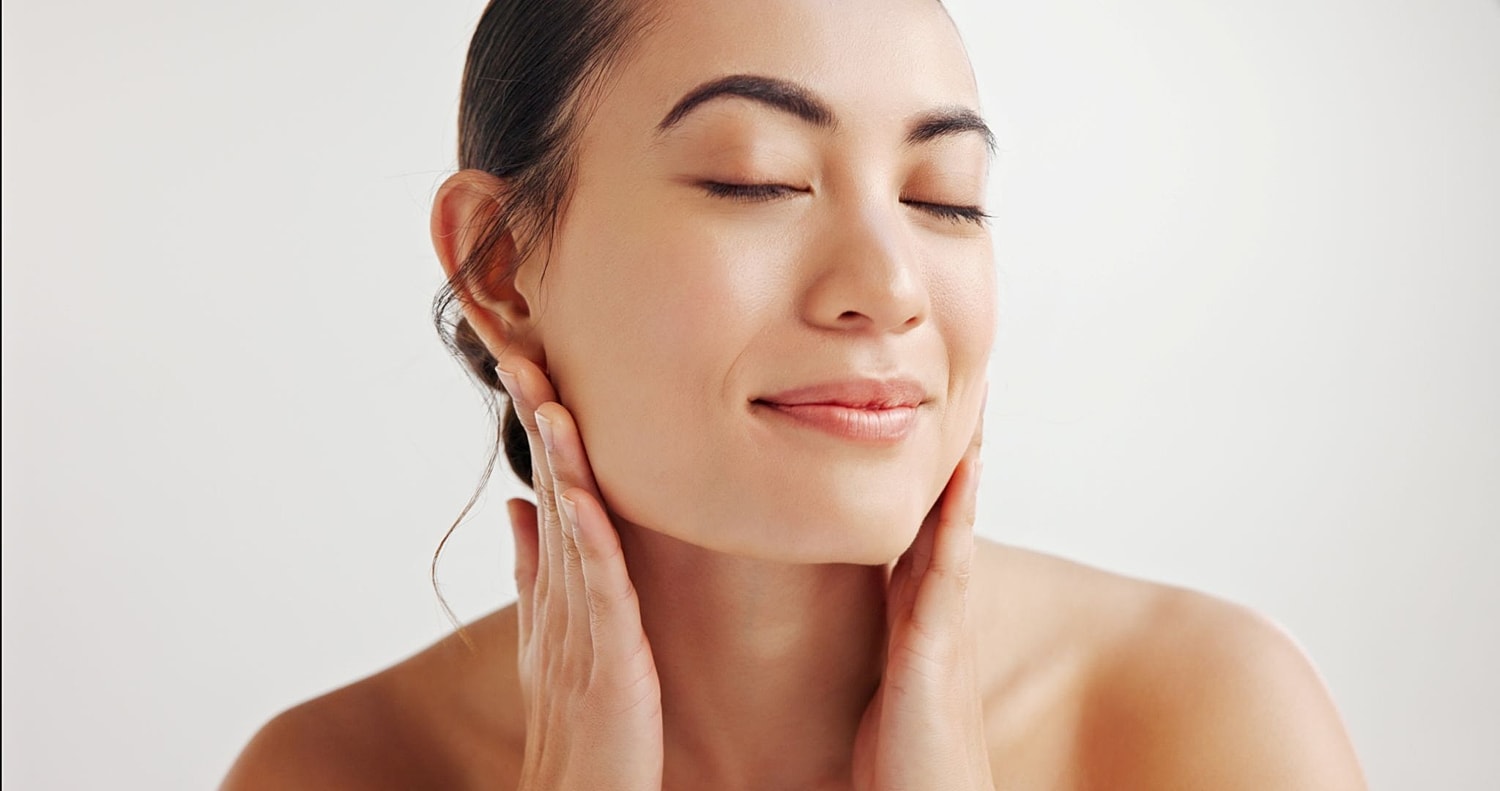 Woman touching her face with smooth skin, representing medical-grade skincare and over-the-counter skincare options.