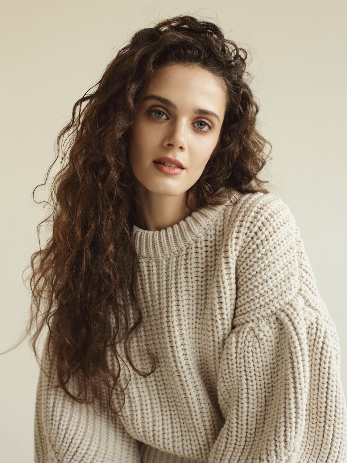 Woman with curly hair in cozy sweater portrait.