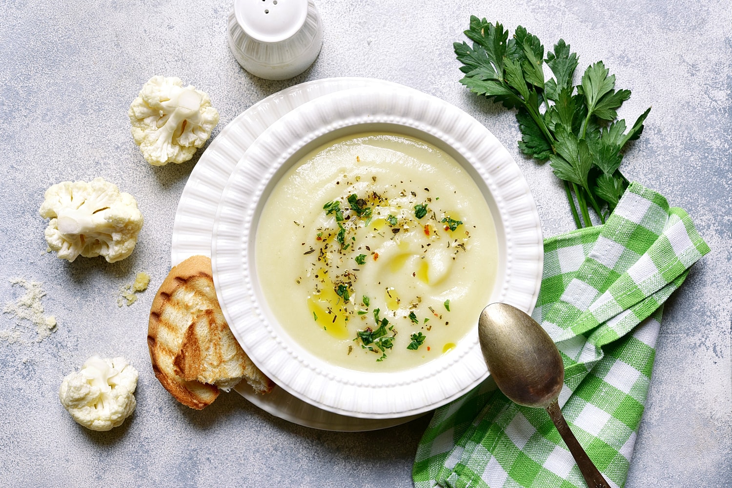 Creamy cauliflower soup with bread and parsley.