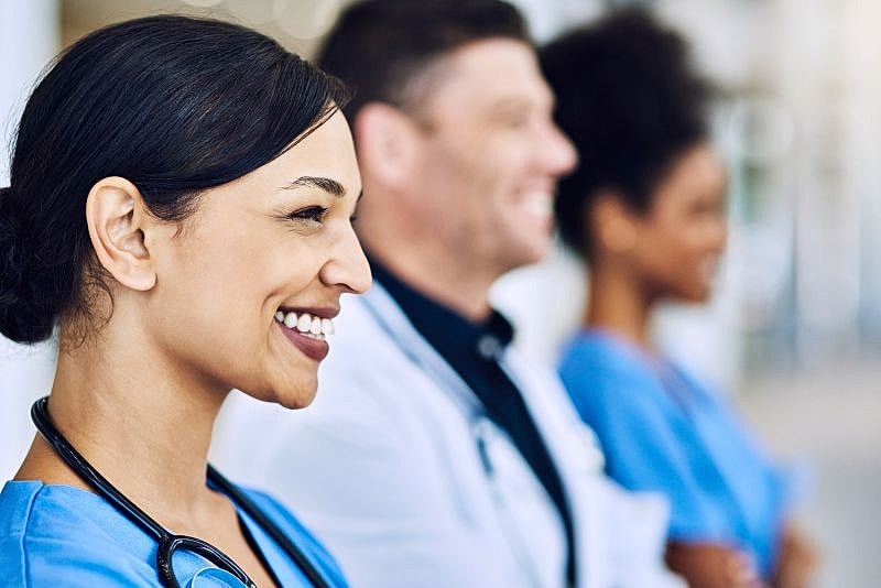 Three nurses smiling while looking off to the right.