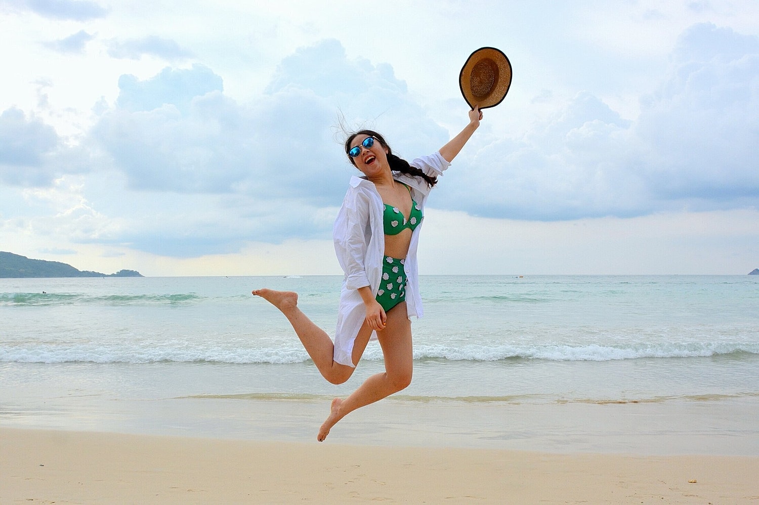 liposuction patient model jumping to catch a frisbee at a beach