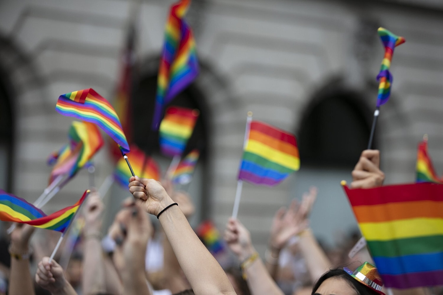 group of people waving small pride flags in the air