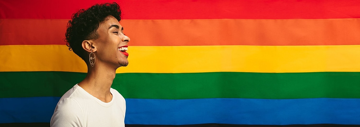 lgbtq individual standing in front of a rainbow