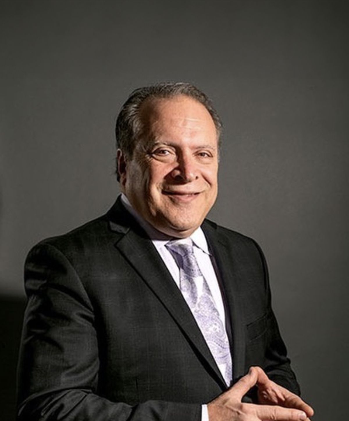 Youthful Images plastic surgeon in Avon, CT, in a suit against a dark background.