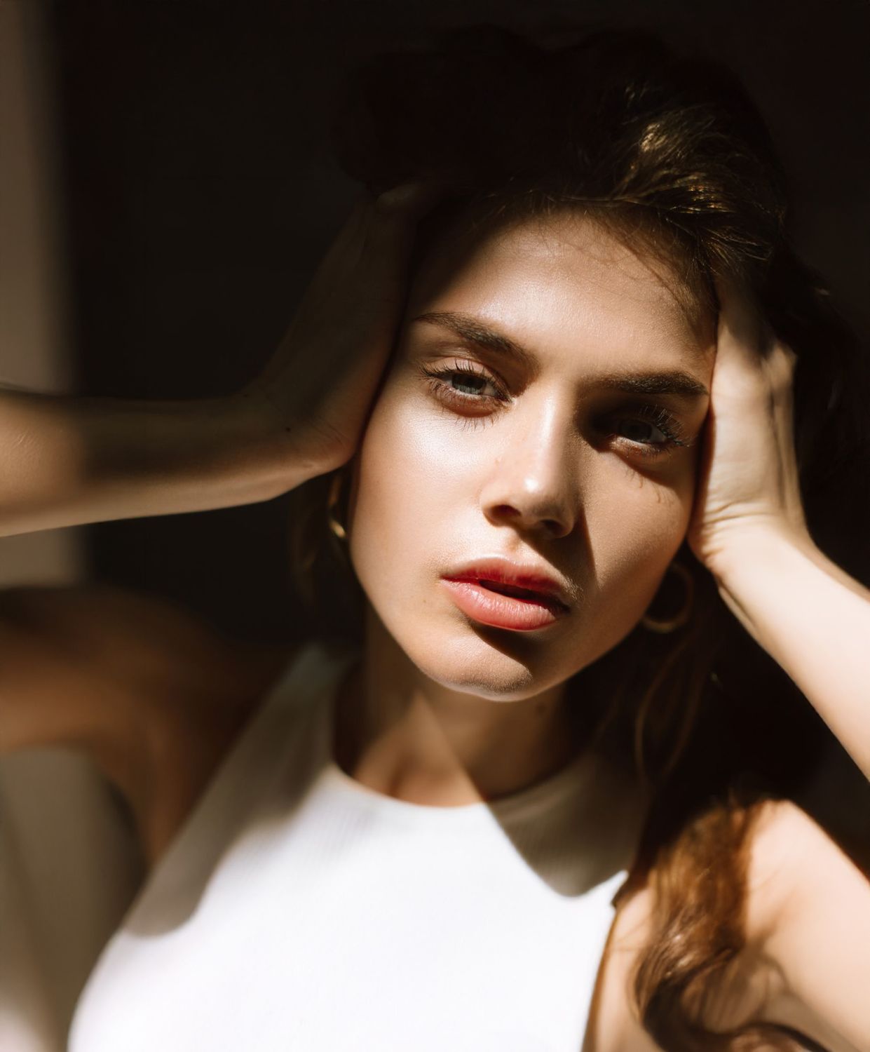 Avon facial fat transfer model with expressive eyes and hands touching face.