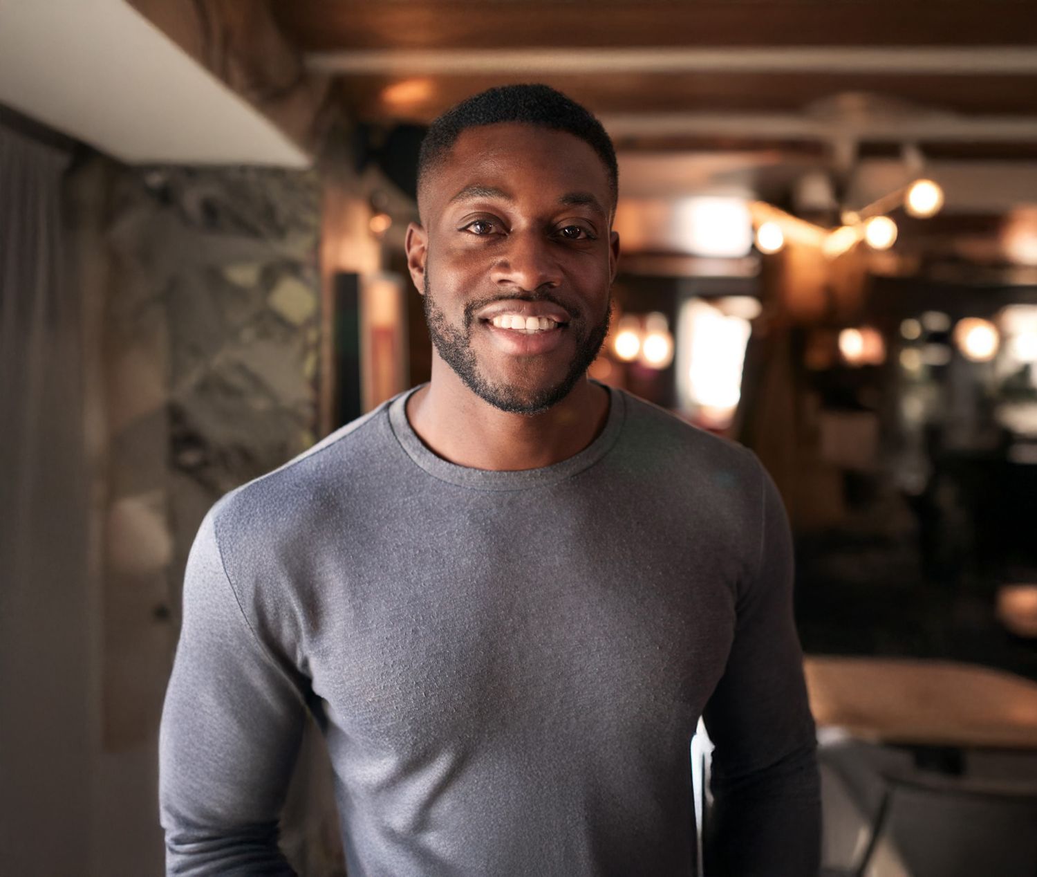 Smiling Farmington male blepharoplasty model in casual gray sweater indoors.