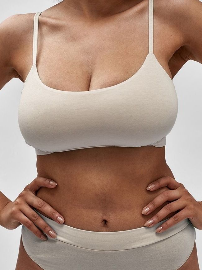 Farmington breast reduction model wearing cream-colored lingerie set.